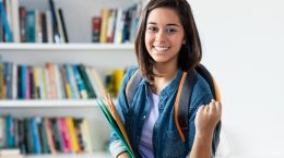 Cheering spanish female student at library of university