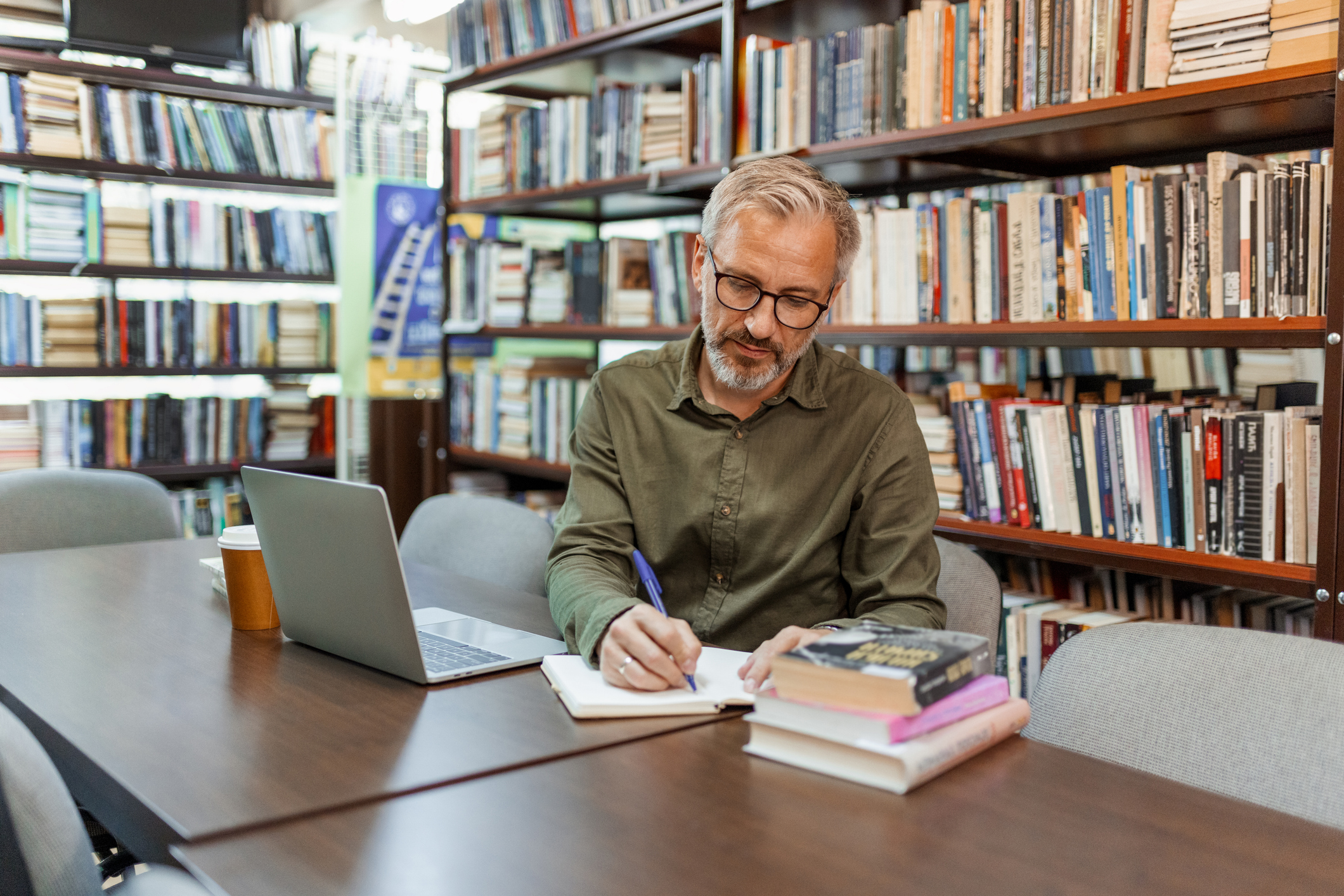 Focused Older Gentleman Taking Notes in Library